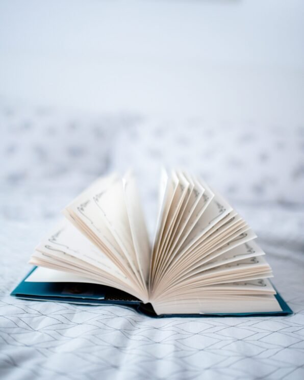 A hardback book lying open on a bed cover